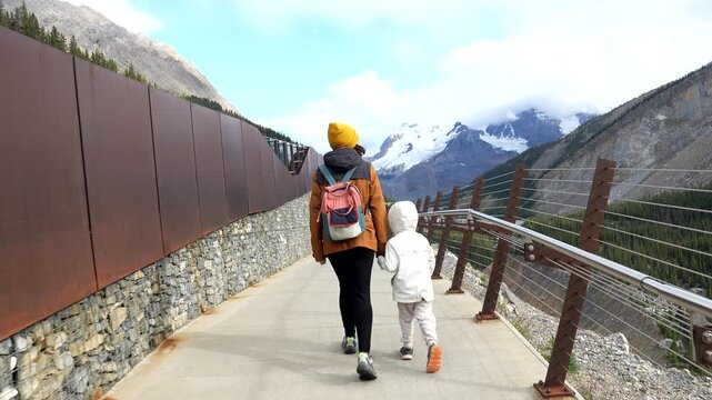 Mother and her child, hand in hand, embark on an unforgettable journey across the columbia icefield skywalk, surrounded by the breathtaking panorama of the canadian rockies