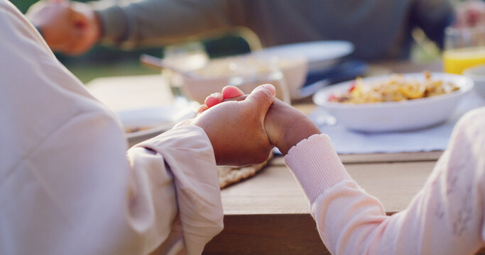 Lunch, backyard and family holding hands by table to pray at celebration, gathering and festive dinner. Christmas, closeup and parents with child with faith, religion and grace for meal in holiday