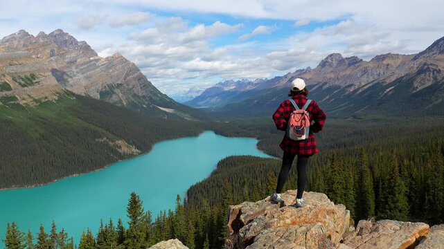 Majestic peyto lake unfolds before a tourist standing on a rocky outcrop, showcasing the turquoise waters and surrounding canadian rockies in banff national park