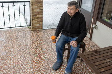 Senior male practicing light fitness routine on patio near house door supporting healthy lifestyle and independence.
