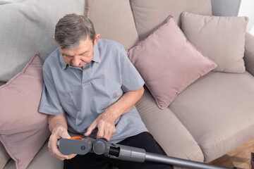 Elderly man checking vacuum cleaner at home