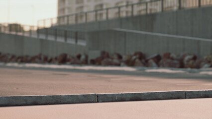 A group of skateboarders performs tricks on a smooth concrete surface as the sun sets behind modern buildings. The warm glow creates a vibrant atmosphere for the evening skate session. © icetray