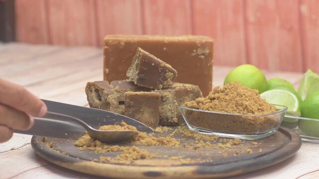 Hand scoops brown sugar with limes and blocks on a wooden board