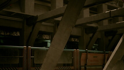 Fototapeta premium A group of explorers wanders through a vast, dimly lit underground facility. The concrete beams and intricate structures highlight a unique blend of industrial design and functionality.