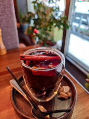 Close-up of mulled wine in a glass cup with cinnamon stick, cloves and orange slices. Traditional hot spiced red wine, cozy winter drink served in a caf&eacute;, perfect for Christmas and holiday atmosphere.