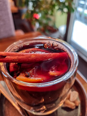 Close-up of mulled wine in a glass cup with cinnamon stick, cloves and orange slices. Traditional hot spiced red wine, cozy winter drink served in a caf&eacute;, perfect for Christmas and holiday atmosphere.