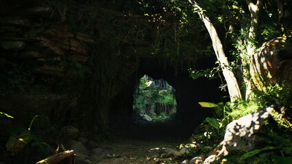 Hidden behind rocky formations, a dark cave leads to a stunning view of vibrant greenery. Sunlight filters through, illuminating the path and surrounding foliage. Natures beauty unfolds invitingly.