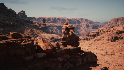 Beneath a golden sky, unique rock structures tower over the barren desert ground. Sunlight illuminates the rugged terrain, showcasing the beauty of nature in this serene landscape.