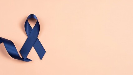 Deep navy blue satin ribbon tied in a bow on a plain peach background, symbolizing awareness and support.