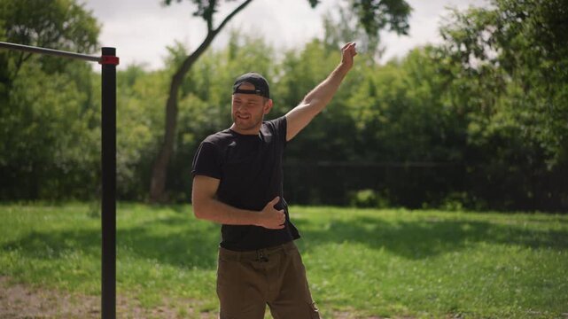 Dynamic Workout Scene, Energetic Individual Performing Torso Swings Beside Exercise Bars In Sunlight, Outdoor Fitness Enthusiast Engaging In Dynamic Arm Swings During Warmup Before Training Session