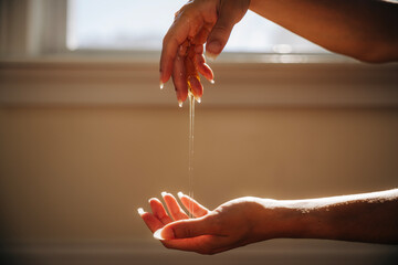 Hands pouring honey in warm sun light