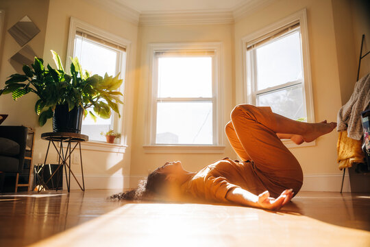 Woman lies on sunny hardwood floor in a peaceful morning moment