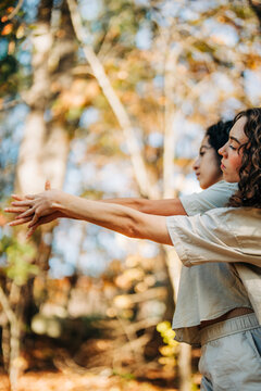 Women stretching arms together in forest concentrating on wellness