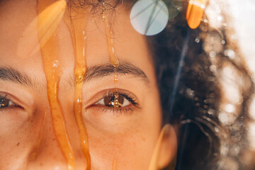 Woman's face with honey dripping on eye for skincare