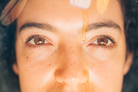 Woman's face with honey dripping on forehead for spiritual ritual