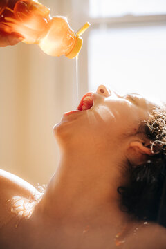 Honey being poured into open mouth in warm natural light