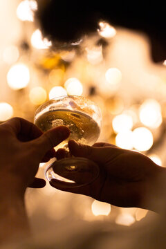 Champagne glass held in front of a chandelier lights