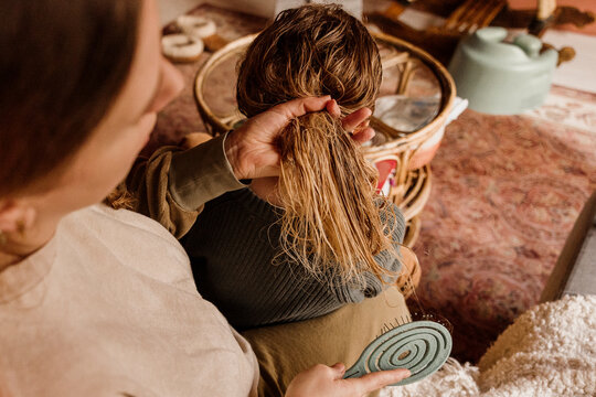 Woman brushing child&rsquo;s wet hair in cozy indoor setting