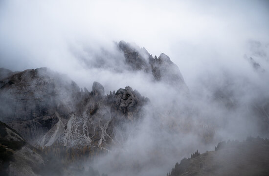 Fog rolling over rugged Dolomites mountains and rocky alpine slopes