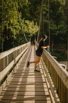 Young woman leans on bridge railing, enjoying view in sunlight