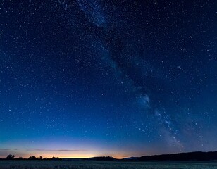 Naklejka premium Vast Starry Night Sky Over a Dark Horizon with a Gentle Glow on the Horizon