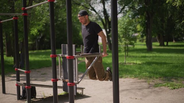 Man Performing Dips Among Green Trees Outdoors, Bodyweight Exercise In Park With Green Surroundings, Individual Engaging In Parallel Bar Dips Amid Nature During Outdoor Fitness Routine