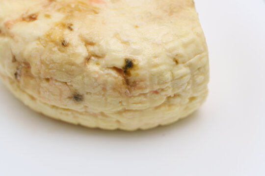 A piece of spoiled cheese is shown on a white plate