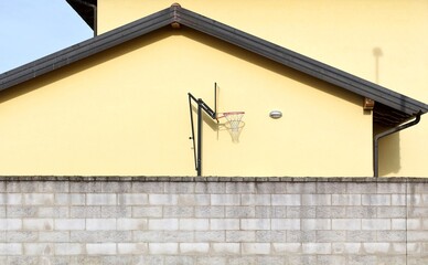 Portable basketball hoop for fun and training behind a fence of a building 