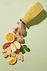 Top view of juice bottle unlabeled with floating lemon slices, ginger and apple slices. Advertising scene of detox juice marketing and modern health visuals