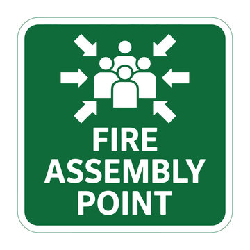 A square green sign with white border displaying fire assembly point information and arrows