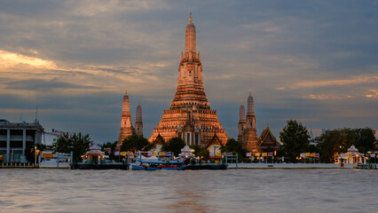 Naklejka premium Stunning sunset view of Wat Arun, the Temple of Dawn, along the Chao Phraya River in Bangkok