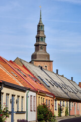 Fototapeta premium Colorful get of historic houses with the church or cathedral bell tower towering above the village roofs on a sunny day in Ystad, Sweden. Relaxed Scandinavian small town travel, high quality of life