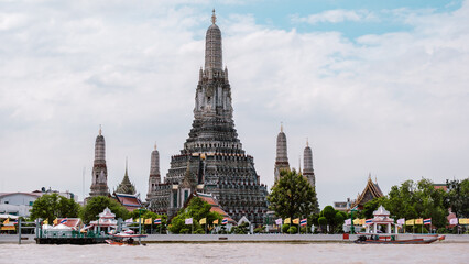 Obraz premium Sunrise over Wat Arun temple in Bangkok reflecting on the river, showcasing Thailands beauty