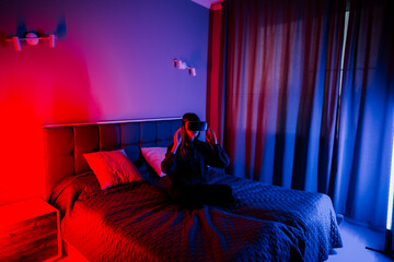 Young woman experiences virtual reality in a bedroom with dim lighting and curtains
