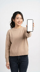 Fototapeta premium Happy Asian woman age 25–32, modern casual fashion, presenting empty smartphone screen toward camera, clean studio background, bright commercial lighting, realistic photography.