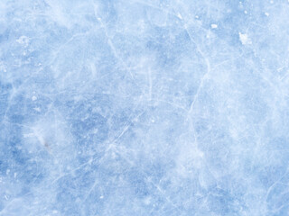 A background of blue ice with scratches and cracks. The frozen surface of a lake, a Christmas winter skating rink. A textured backdrop for New Year's, winter sports, and entertainment.