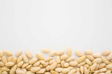 Almond nuts on light gray table background. Closeup. Empty place for text. Top down view.