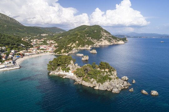 Aerial view of a lush island with rocky outcrops meets the turquoise sea, framed by the coastal town and verdant hills, Panagia, Thasos Regional Unit, Greece.