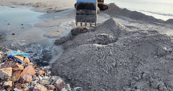 excavator moving sand on a beach for shoreline maintenance.