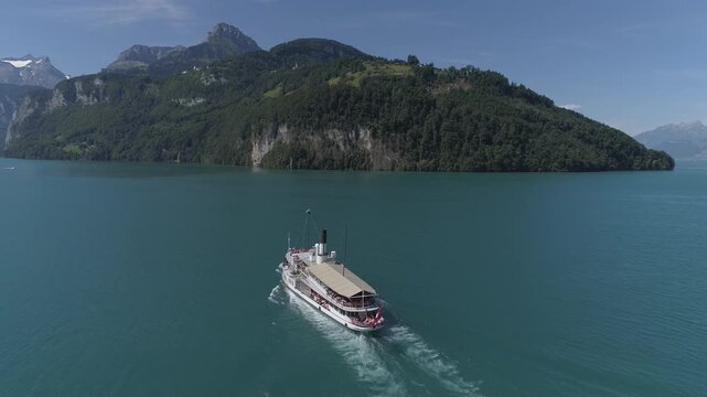 Aerial view of a passenger boat sailing on the serene, turquoise waters of Lake Lucerne against a backdrop of majestic mountains, Ingenbohl, Schwyz, Switzerland.