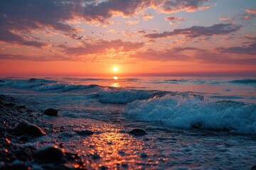Stunning sunrise over the calm sea with waves gently lapping at the rocky shore, creating a serene morning atmosphere
