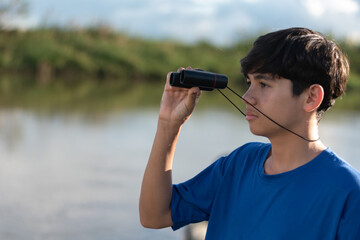 A boy standing and watching birds by river, exploring nature life and outdoor animals. Igniting curiosity and the spirit of scientific discovery.