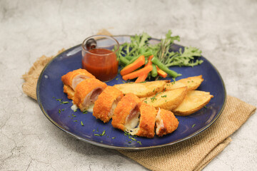 Chicken Cordon Bleu with Potato Wedges and Vegetables on Blue Plate