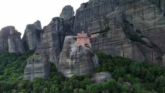 Aerial view of the breathtaking Meteora Monastery perched atop towering rock formations amidst lush greenery, Kalabaka, Trikala, Greece.