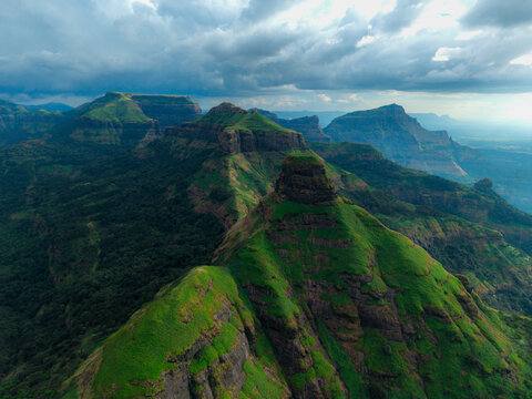 Aerial view of the lush green Western Ghats and mountains with dramatic cloudscape casting shadows across the landscape, Nashik, Maharashtra, India.