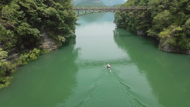 A man in a canoe paddling on a lake surrounded by nature. Aerial view of a canoeist practicing canoeing, a healthy outdoor activity