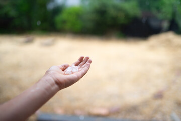 Hand holding hailstones during summer storm