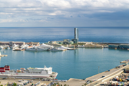 Barcelona, Spain - 07 November 2016: Aerial view of the shimmering blue harbor, where luxury yachts rest near the iconic Hotel Arts Barcelona, under a sky of soft, diffused light.
