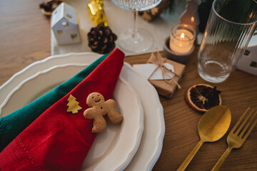 Festive table setting. Homemade Christmas. Gift box, burning candles, red and green napkins. New Year.