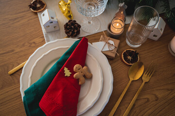 Festive table setting. Homemade Christmas. Gift box, burning candles, red and green napkins. New Year.